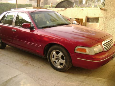 1998 Ford Crown Victoria - This 1998 Ford Crown Victoria sedan is parked in a driveway with a building in the background.