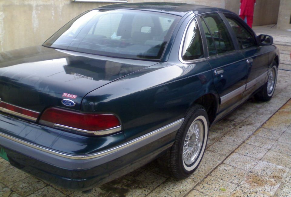 1998 Ford Crown Victoria rear quarter view, dark green sedan with chrome trim and wire wheels