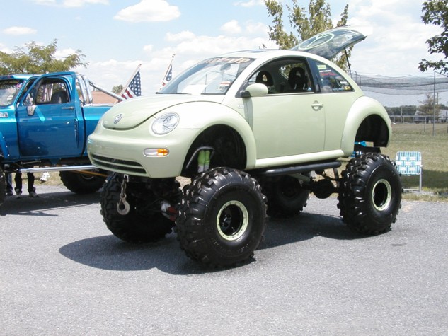 Pale green VW New Beetle monster truck on huge tires and a tube chassis at a car show