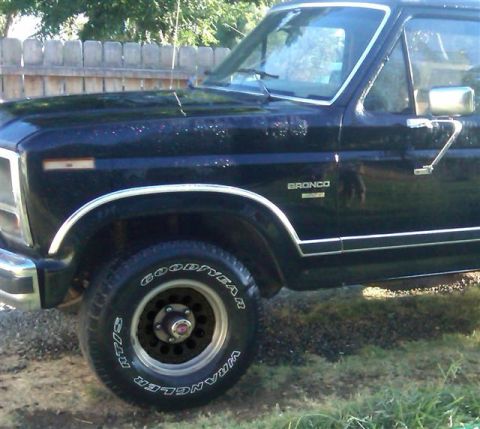 1986 Ford Bronco - Black 1986 Ford Bronco shown from the front quarter angle, with a wooden fence in the background.