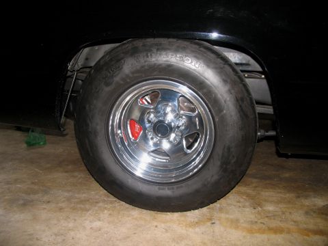 1990 Chevrolet Silverado 1500 - Close-up of a chrome wheel with a red brake caliper and a drag radial tire on a black vehicle.