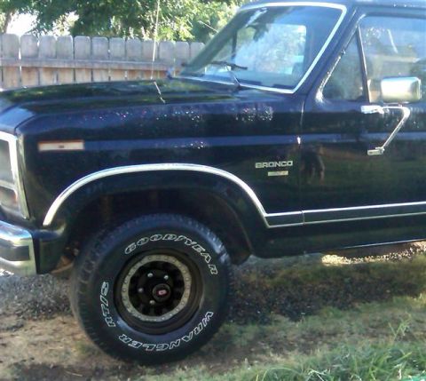 1986 Ford Bronco - Side view of a black 1986 Ford Bronco showing the front fender and door.