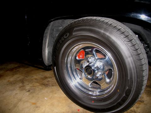 1990 Chevrolet Silverado 1500 - A close-up shot focuses on a shiny chrome wheel and a red brake caliper, hinting at performance upgrades.