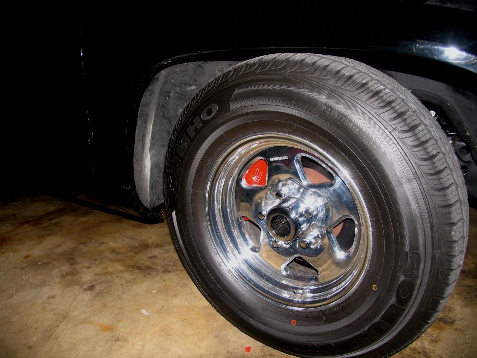 Polished five-spoke mag wheel with Kumho tire on black truck in garage