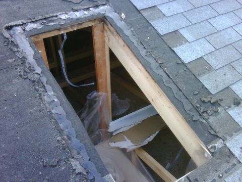 1996 Ford Bronco - A damaged skylight opening reveals exposed wooden framing and surrounding shingles, indicating a need for repair.
