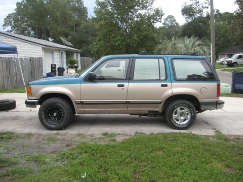 1992 Ford Explorer - A two-tone Ford Explorer is parked on a concrete driveway in front of a house.