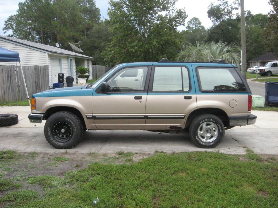 Side view of a tan and teal 1992 Ford Explorer with aftermarket wheels