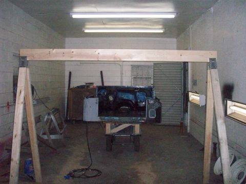 1978 Jeep CJ5 - The body of a Jeep CJ5 is suspended on a stand in a workshop, with its interior exposed.