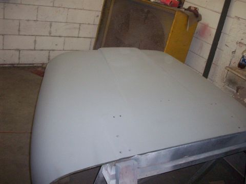 1978 Jeep CJ5 - Jeep hood in primer, ready for paint. Background shows workshop equipment.