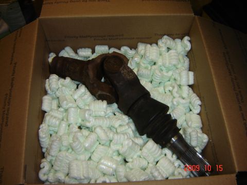 1993 Ford Bronco - A driveshaft part is packed in a box with white packing peanuts, ready for shipping.