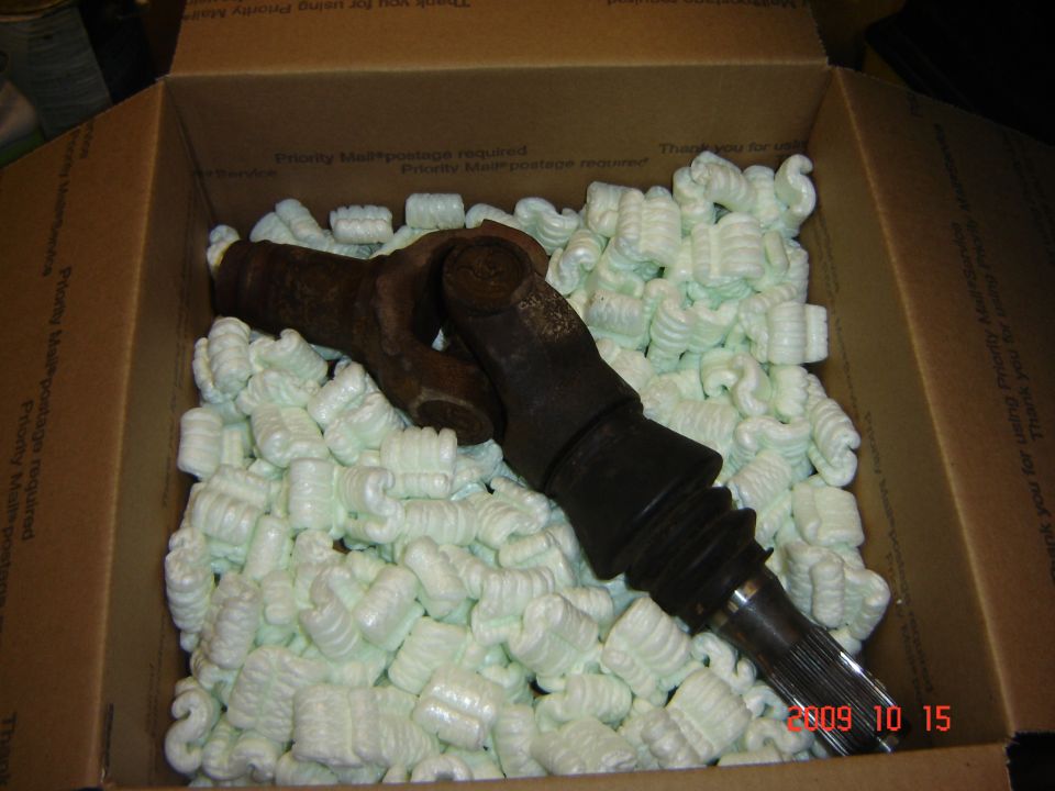 Driveshaft U-joint and splined end in a cardboard box with packing peanuts