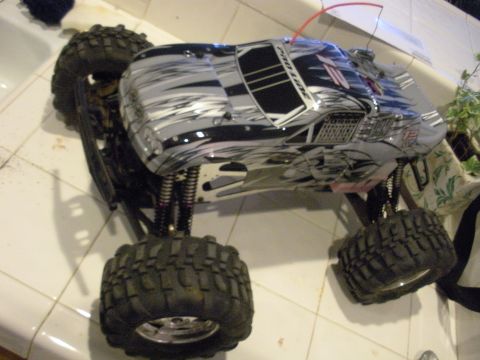 1990 Ford Bronco - A remote control monster truck sits on a tiled surface, showing off its aggressive tire tread and custom body graphics.