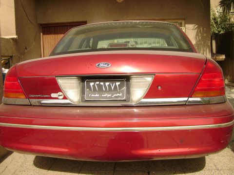 1998 Ford Crown Victoria - Rear view of a red 1998 Ford Crown Victoria, its distinctive taillights and chrome accents.