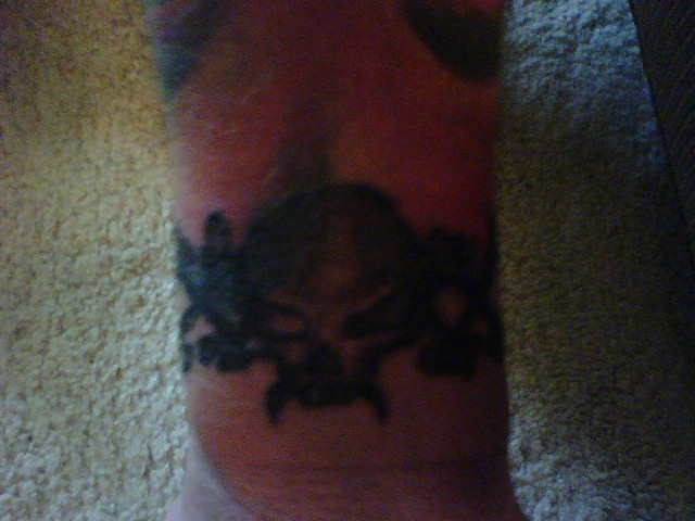 Black tribal tattoo on an arm, possibly a skull with wings