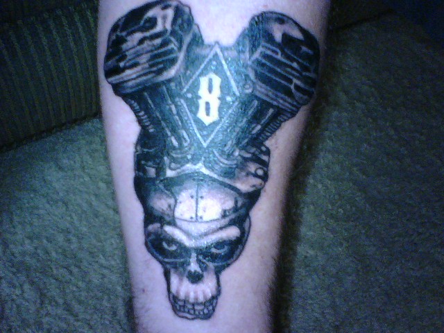 Tattoo of a V-twin motorcycle engine above a skull with the number 8 inside a diamond