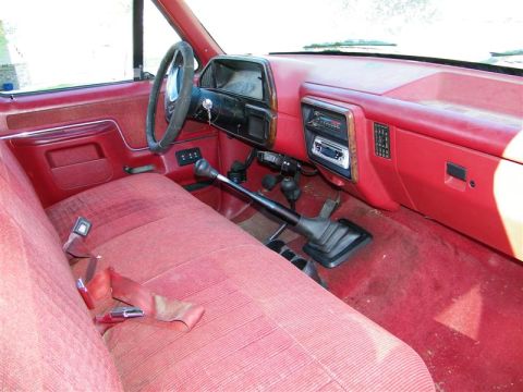 1990 Ford F-350 - The interior of this truck features red upholstery and a manual transmission shifter.