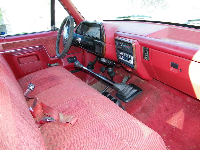 Interior of a 1990 Ford F-350, showing red seats, dashboard, steering wheel, and gear shifter