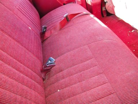 1990 Ford F-350 - Close-up of a red fabric seat with seatbelts, showing interior details. No year-determining features are visible.