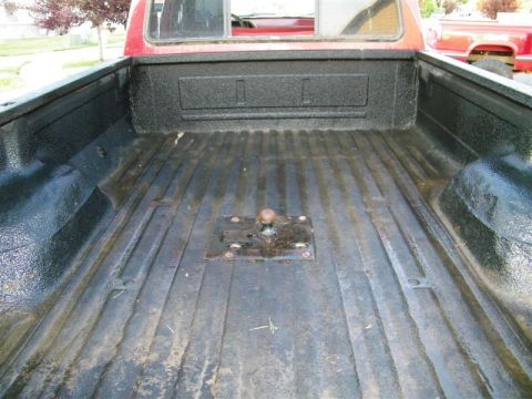 1990 Ford F-350 - The bed of a red 1990 Ford F-350 pickup truck, equipped with a fifth wheel hitch, is shown from the rear.