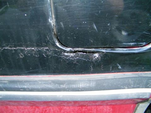 1990 Ford F-350 - Close-up of a damaged door seam on a vehicle, showing cracked and peeling black paint.