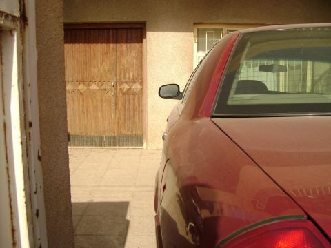 1998 Ford Crown Victoria - A red sedan is parked in front of a wooden garage door, with a watermark visible on the rear bumper.