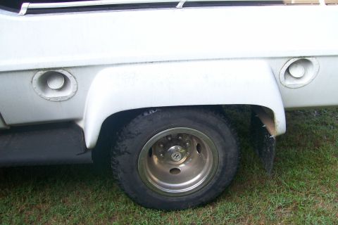1982 Ford E350 - A white truck's side view shows the rear wheel well with dual fuel caps and a chrome rim wheel.