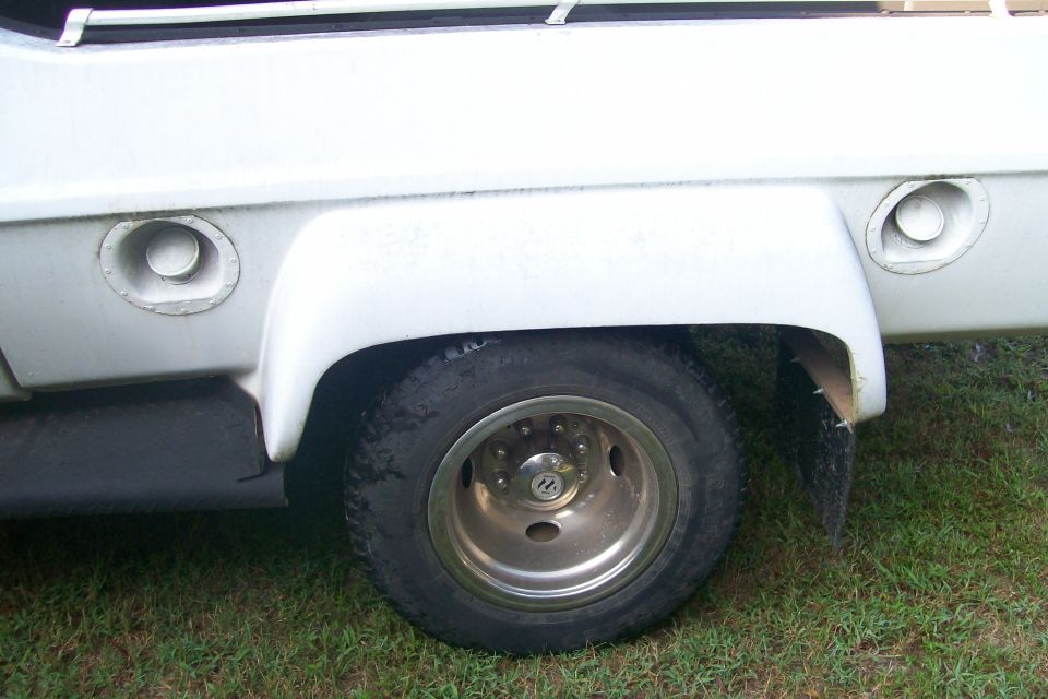 White truck rear wheel well with dual fuel caps and a chrome rim wheel