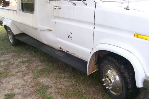 1982 Ford E350 - White van side view with running boards and visible rust damage.
