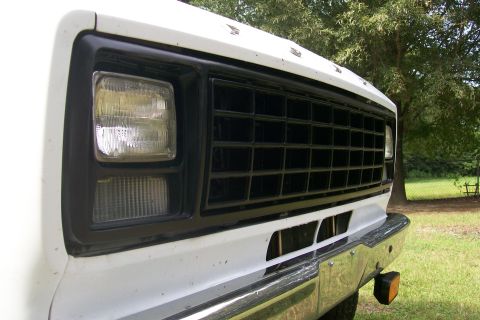 1982 Ford E350 - The front grille and headlight assembly of a white van is shown in this close-up shot.