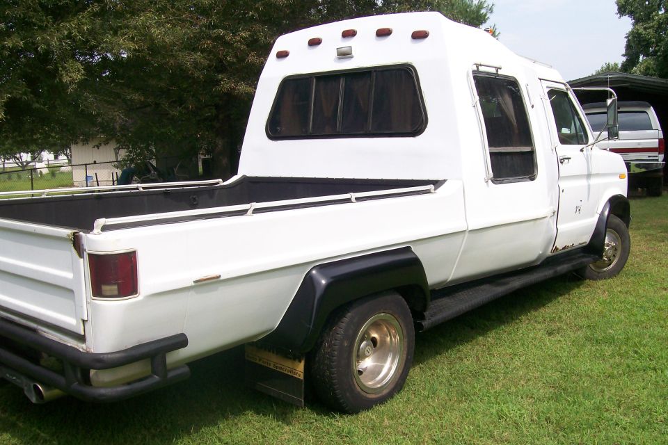 1982 Ford E350 custom pickup truck with camper conversion, rear 3/4 view. Another vehicle is partially visible in the background