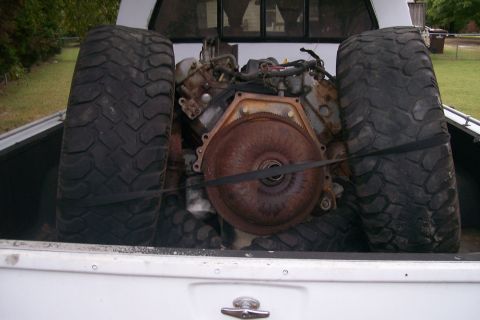 1992 Ford C-350 (Centurion Conversions) - Engine and large tires are loaded in the bed of a pickup truck.