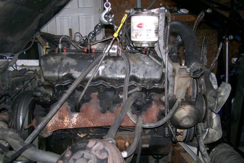1992 Ford C-350 (Centurion Conversions) - Engine assembly, likely undergoing maintenance or replacement, is suspended by a chain hoist. A prominent oil filter is visible.