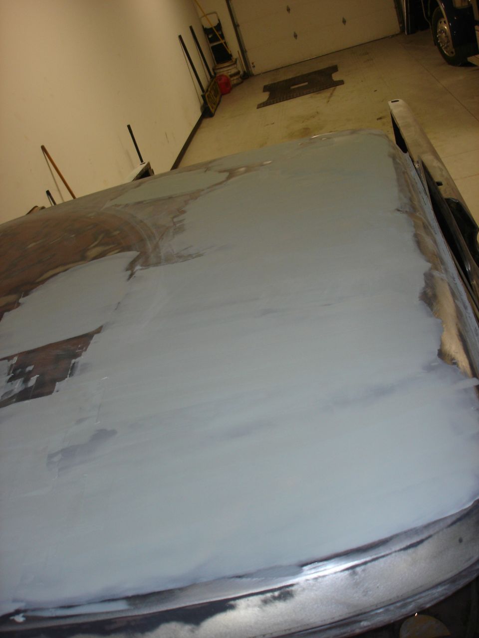 Car hood covered in body filler, showing repair work in progress