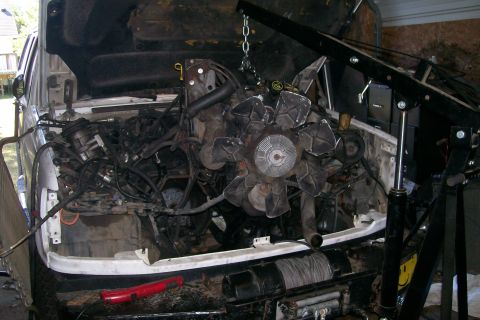 1992 Ford C-350 (Centurion Conversions) - The engine is suspended by a chain and hoist, ready for removal from the engine bay.