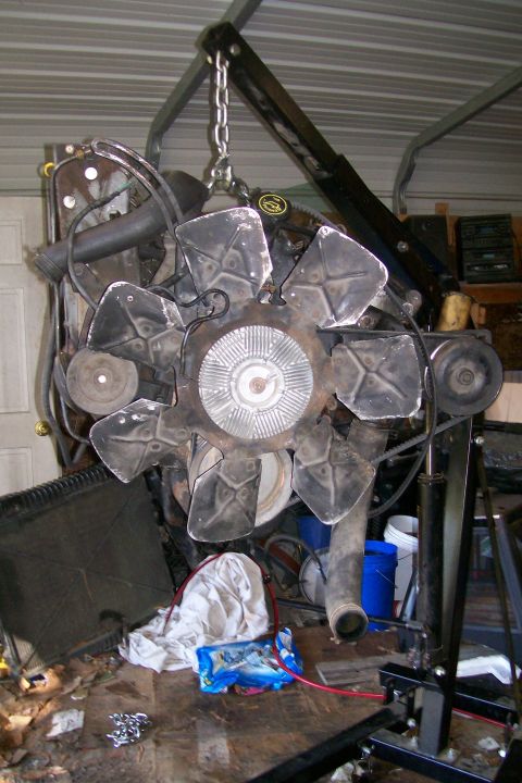 1992 Ford C-350 (Centurion Conversions) - An engine assembly is shown suspended by a chain hoist, with a large fan and belts visible.