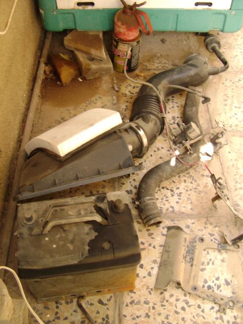 1998 Ford Crown Victoria - Car parts laid out on the floor, including an air intake system and a car battery.