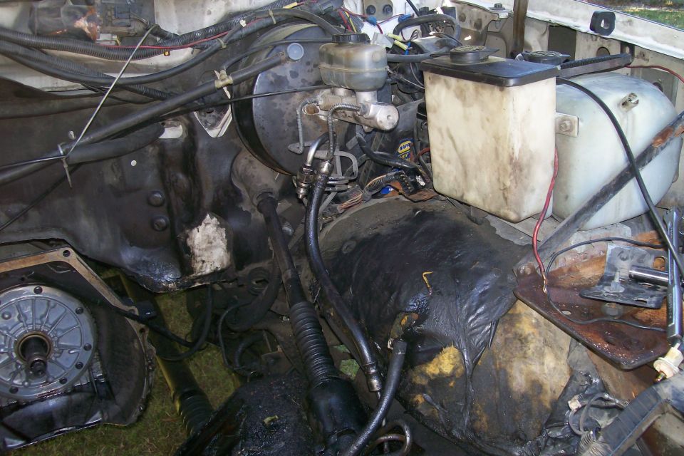 Engine bay with master cylinder, brake booster, and fluid reservoirs. Some transmission components visible