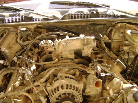 1998 Ford Crown Victoria - Close-up view of a dusty engine bay, showing the intake manifold and alternator.