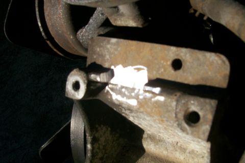 1992 Ford C-350 (Centurion Conversions) - Close-up of a rusted metal bracket with a bolt, likely from a vehicle's suspension or engine bay.