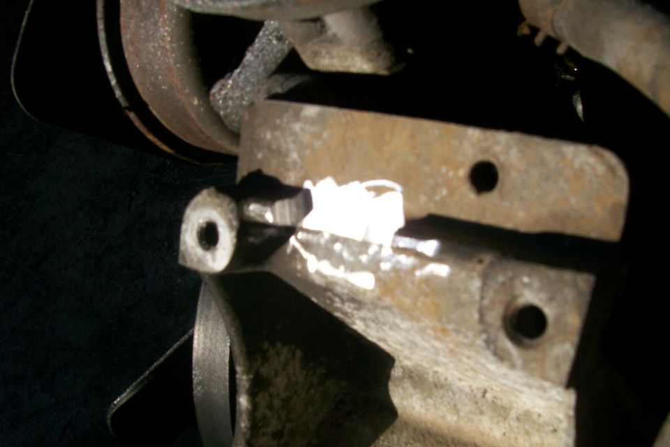 Close-up of a rusted metal bracket with a bolt and some white markings