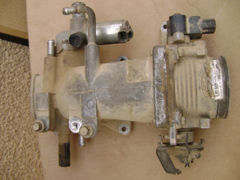 1998 Ford Crown Victoria - A dirty Ford throttle body assembly is shown, with visible hoses and electrical connectors.