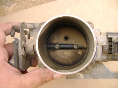 1998 Ford Crown Victoria - A dirty throttle body is shown, with visible carbon buildup around the butterfly valve.