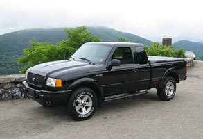 1996 Ford Crown Victoria - A black Ford Ranger pickup truck is parked on a paved surface with a scenic mountain view.