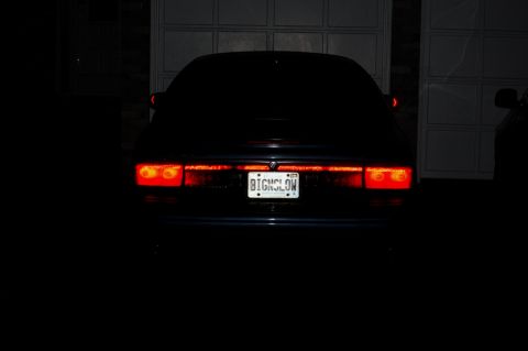 1985 Mercury Grand Marquis - The rear of a dark sedan is visible with its taillights illuminated.