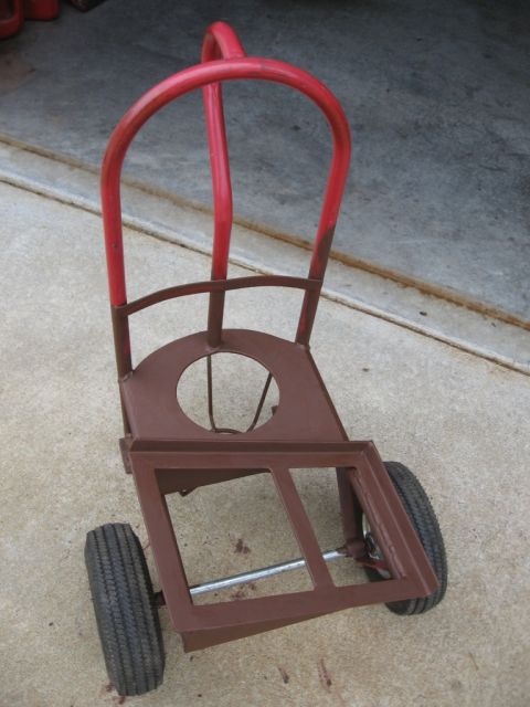 1995 Ford F-150 - A welding cart with a red frame and brown metal body sits on a concrete surface.