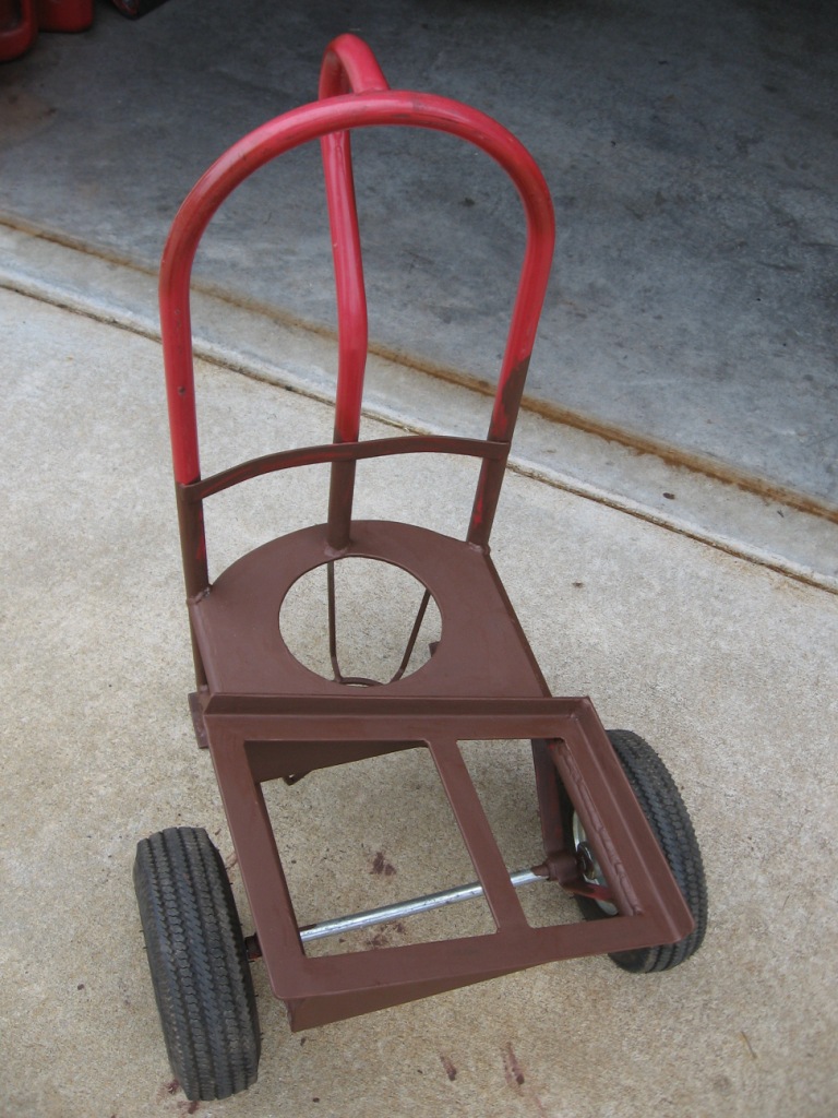 Red and brown metal welding cart with two wheels