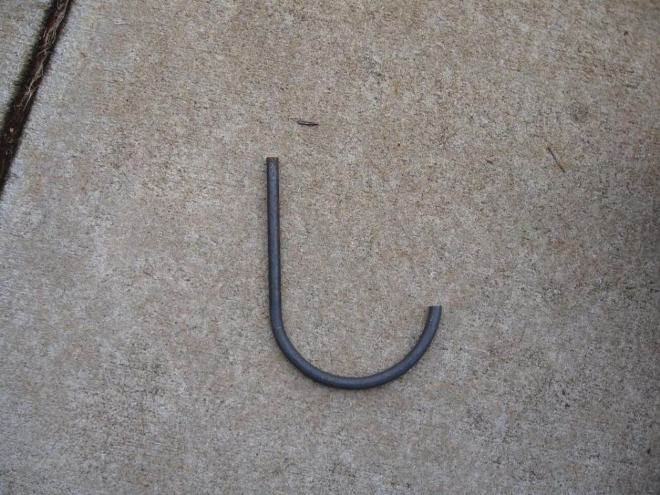 Dark gray metal hook lying on concrete