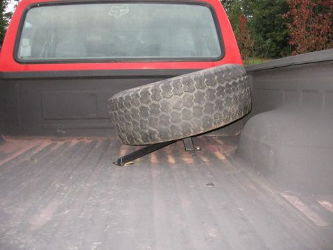 1995 Ford F-150 - Spare tire secured in the bed of a red pickup truck.