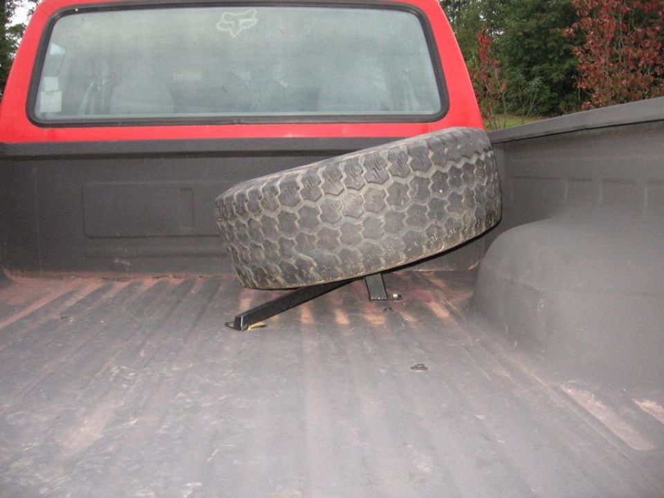 Spare tire mounted in the bed of a red truck