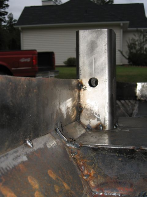 1995 Ford F-150 - A close-up of a welded metal structure, possibly a hitch receiver, with a red Ford truck in the background.